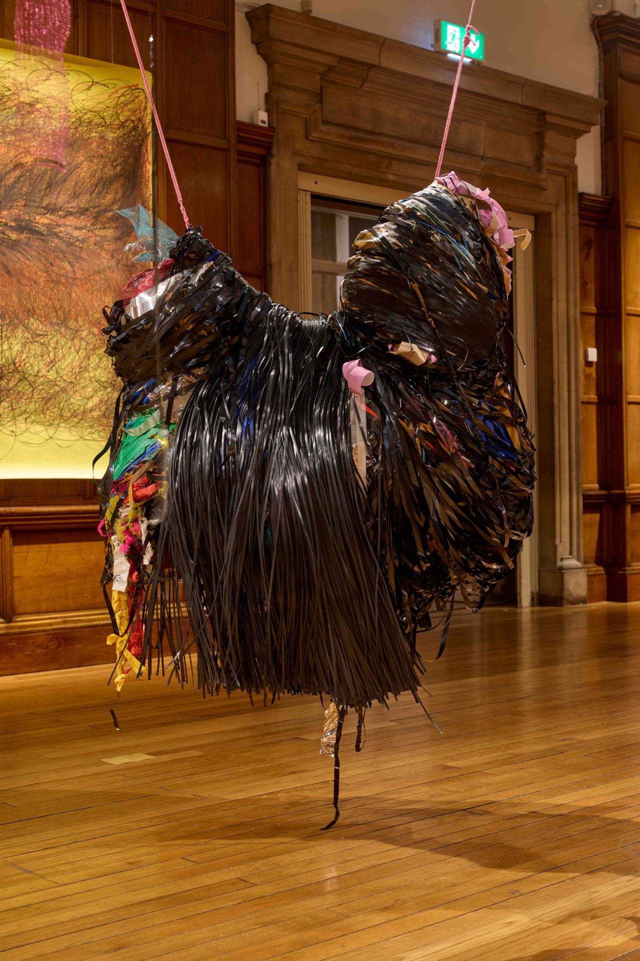 Black hanging sculpture made out of vhs tape and other materials