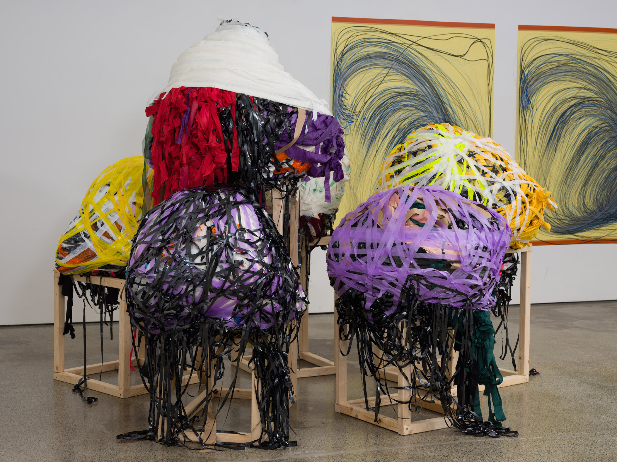 Five round sculpture made out of tape, paper and VHS reels, sat on wooden frames.