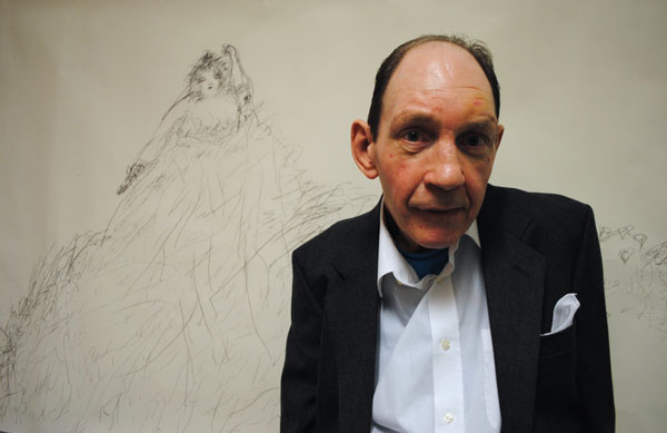 Artist Nigel Kingsbury wearing a suit standing in front of a drawing.