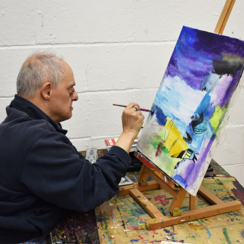 ActionSpace Artist Ali Kamalati sitting down painting a canvas.