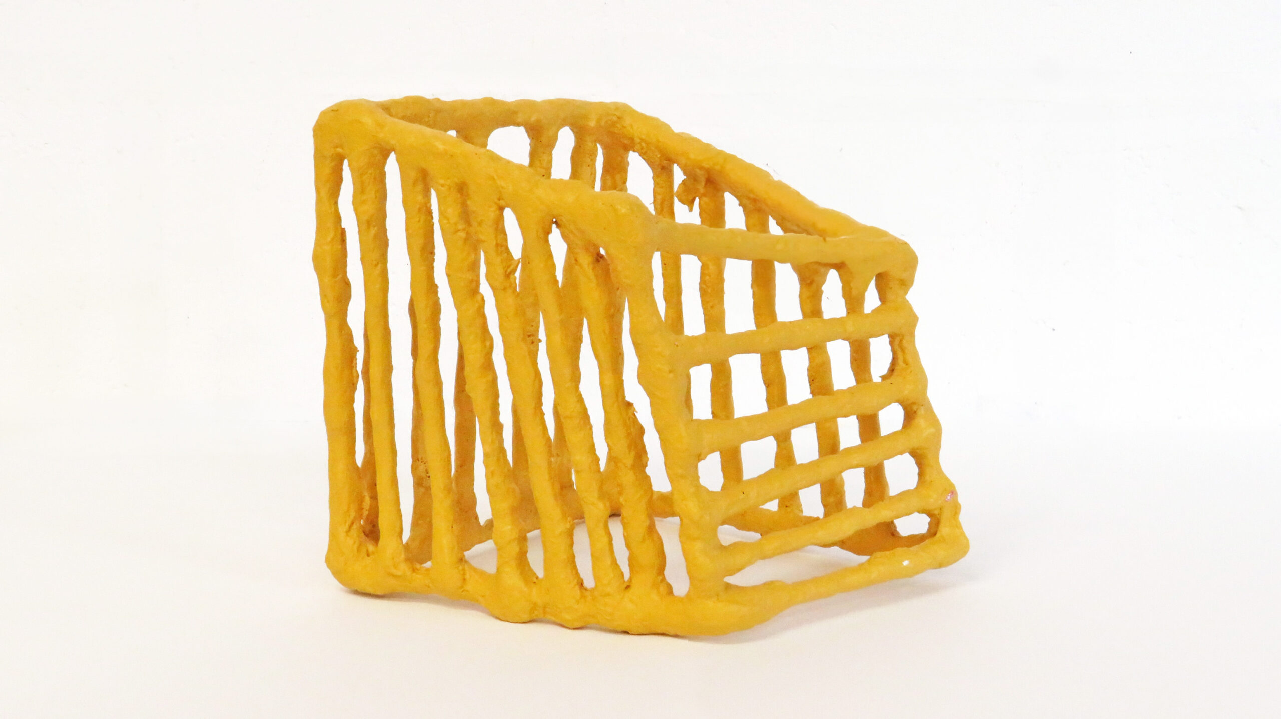 A small yellow sculpture with thick constructed lines in an abstract shape.