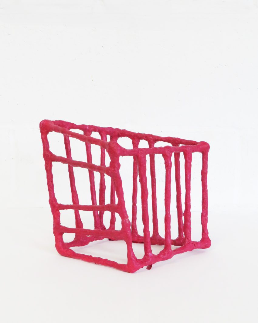 A small magenta sculpture with thick constructed lines in an abstract shape.