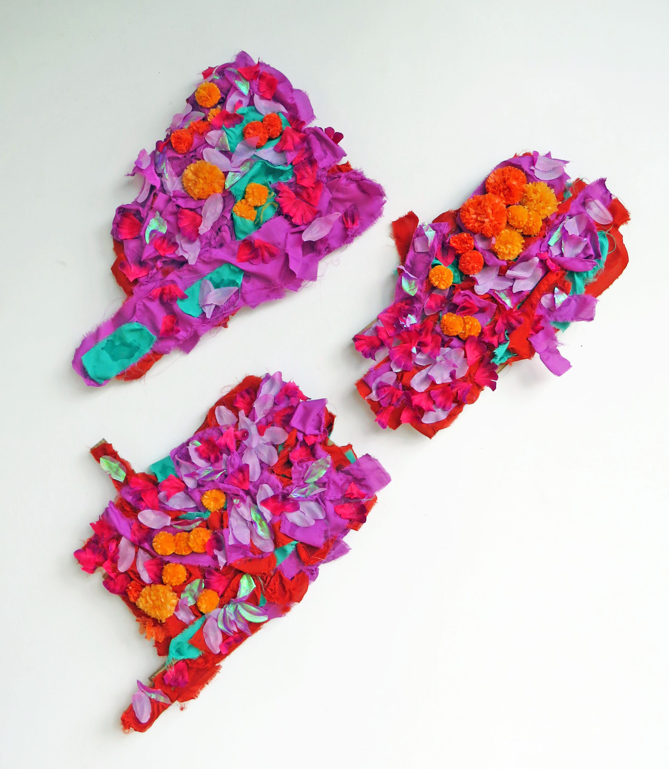 A trio of artworks against a white background. Colourful, abstract, textile sculptures.