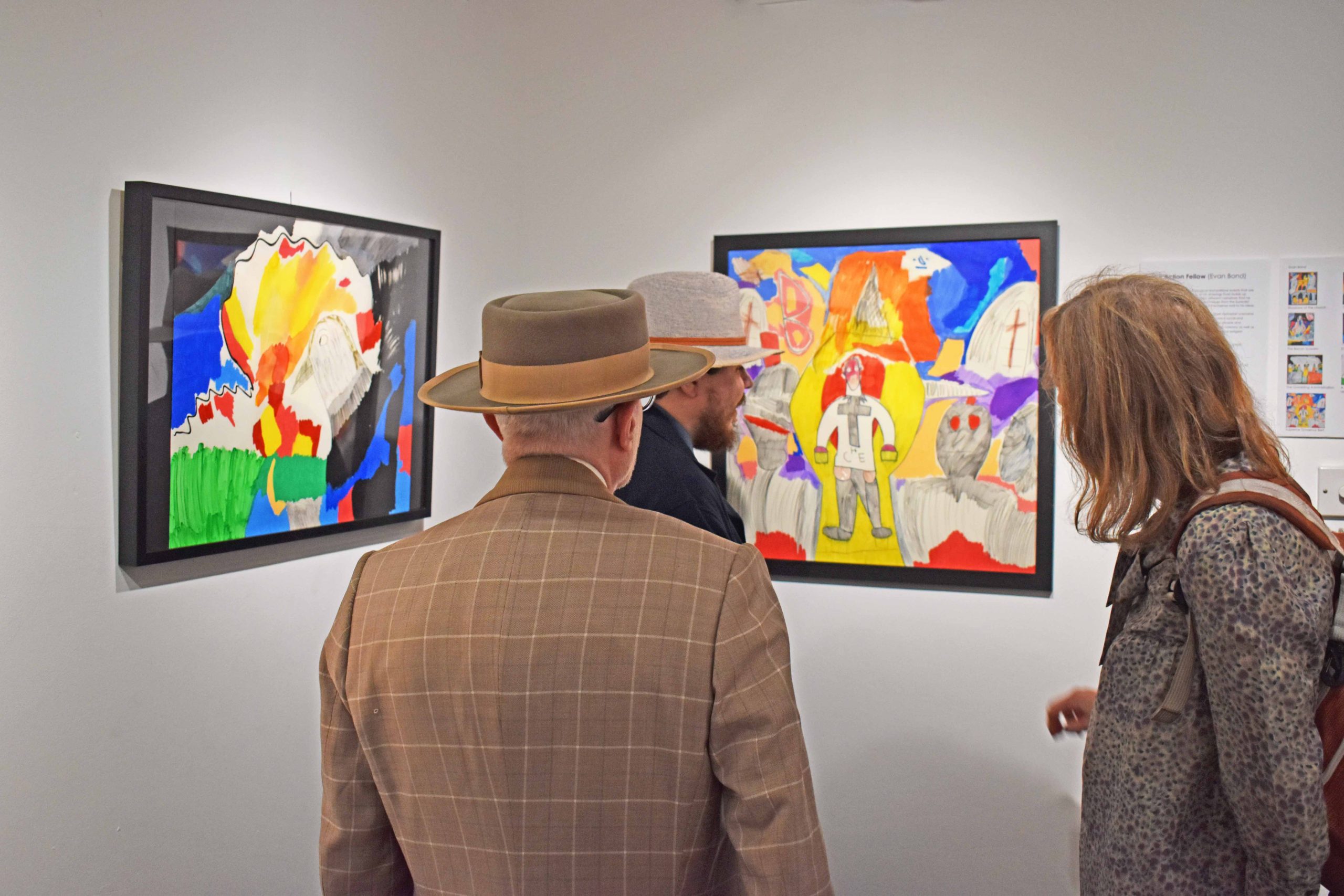 Evan's work on the walls of a gallery, with visitors observing.