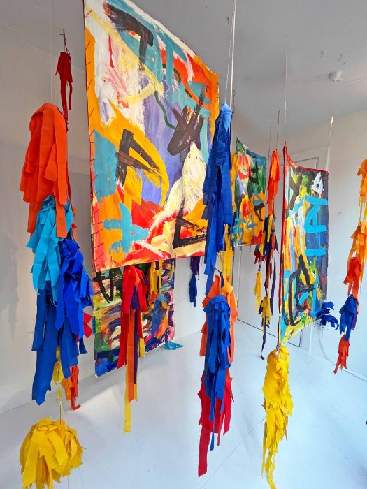 Colourful mixed media pieces hanging in a gallery space.