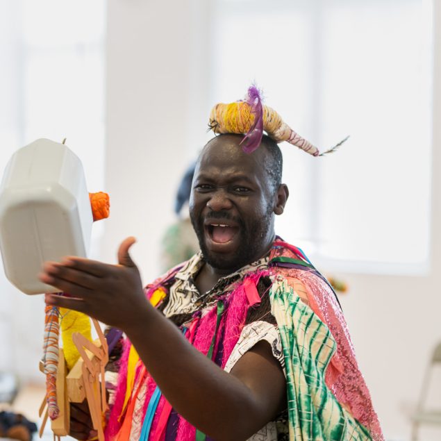 Artist Andrew Omoding playing an instrument during a performance.