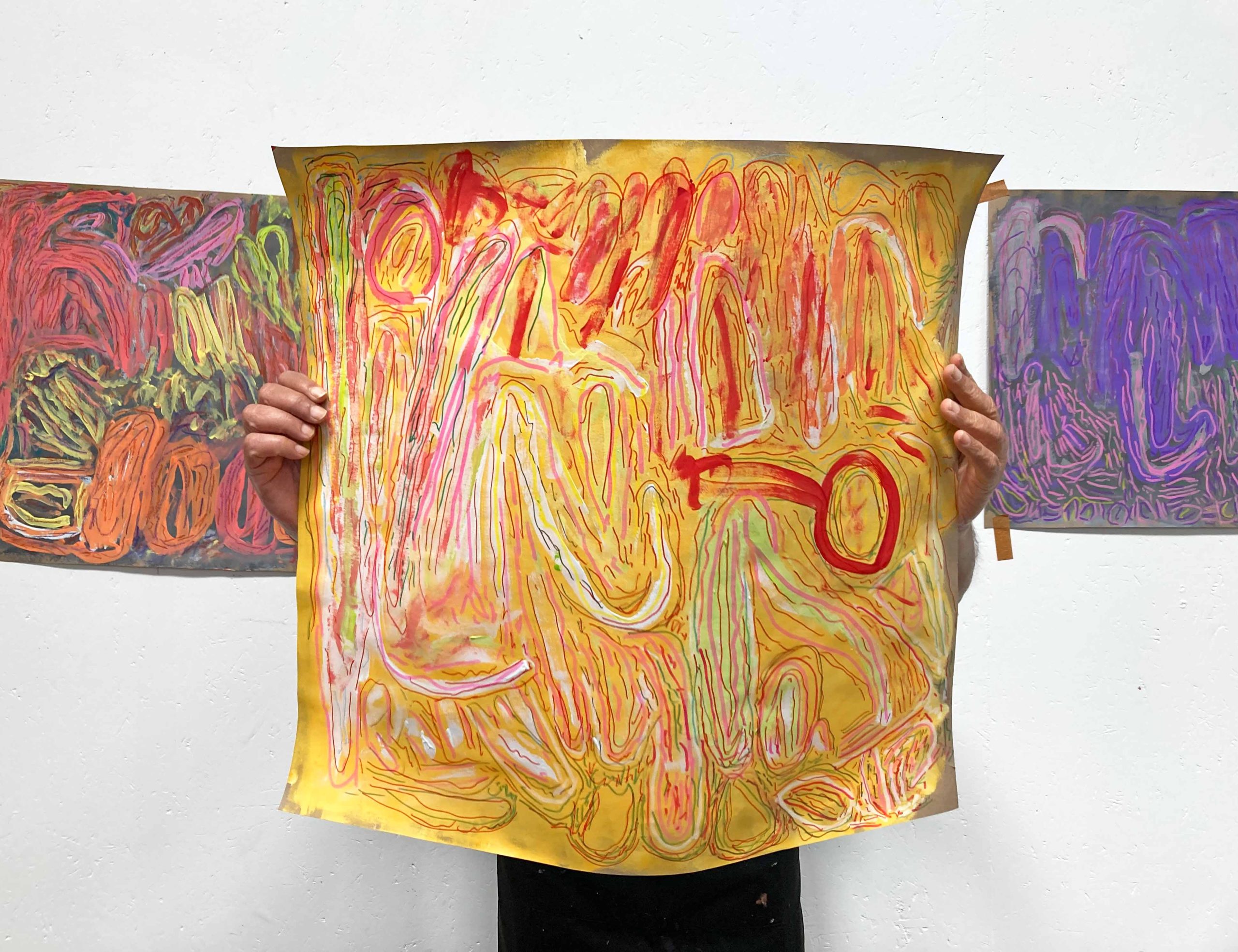 Artist holding up an abstract painting in front of them.
