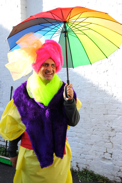 Pardip Kapil holding a rainbow coloured umbrella and brightly coloured clothes