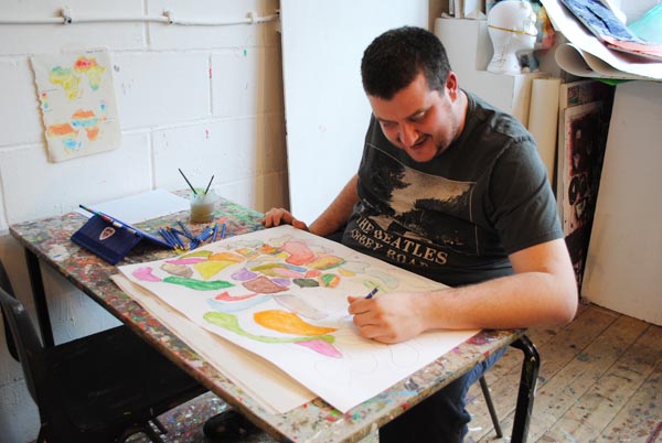 A man sitting down drawing on paper.