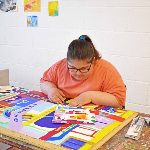 A woman working on a painting in a studio.