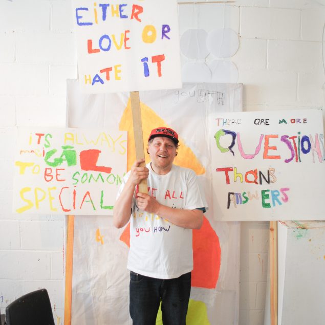 Tony standing with his artwork in the studio.