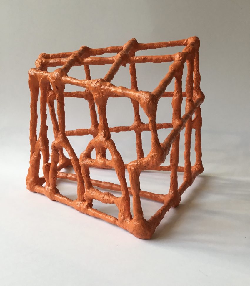 A small orange sculpture with thick constructed lines in an abstract shape.