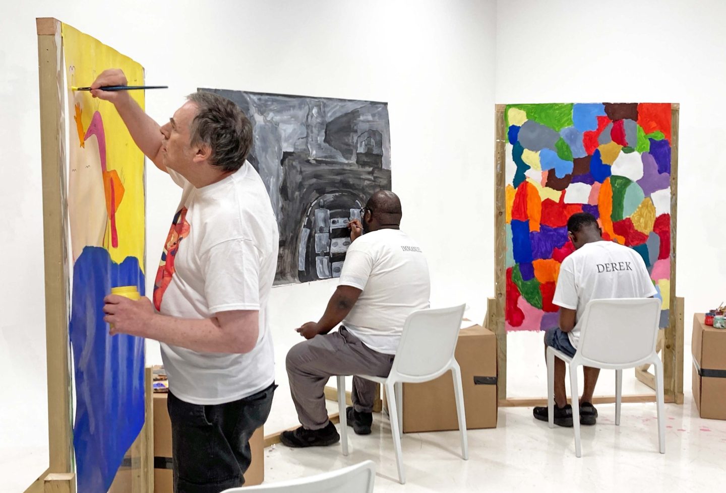 Three male artists busy painting in a white space.