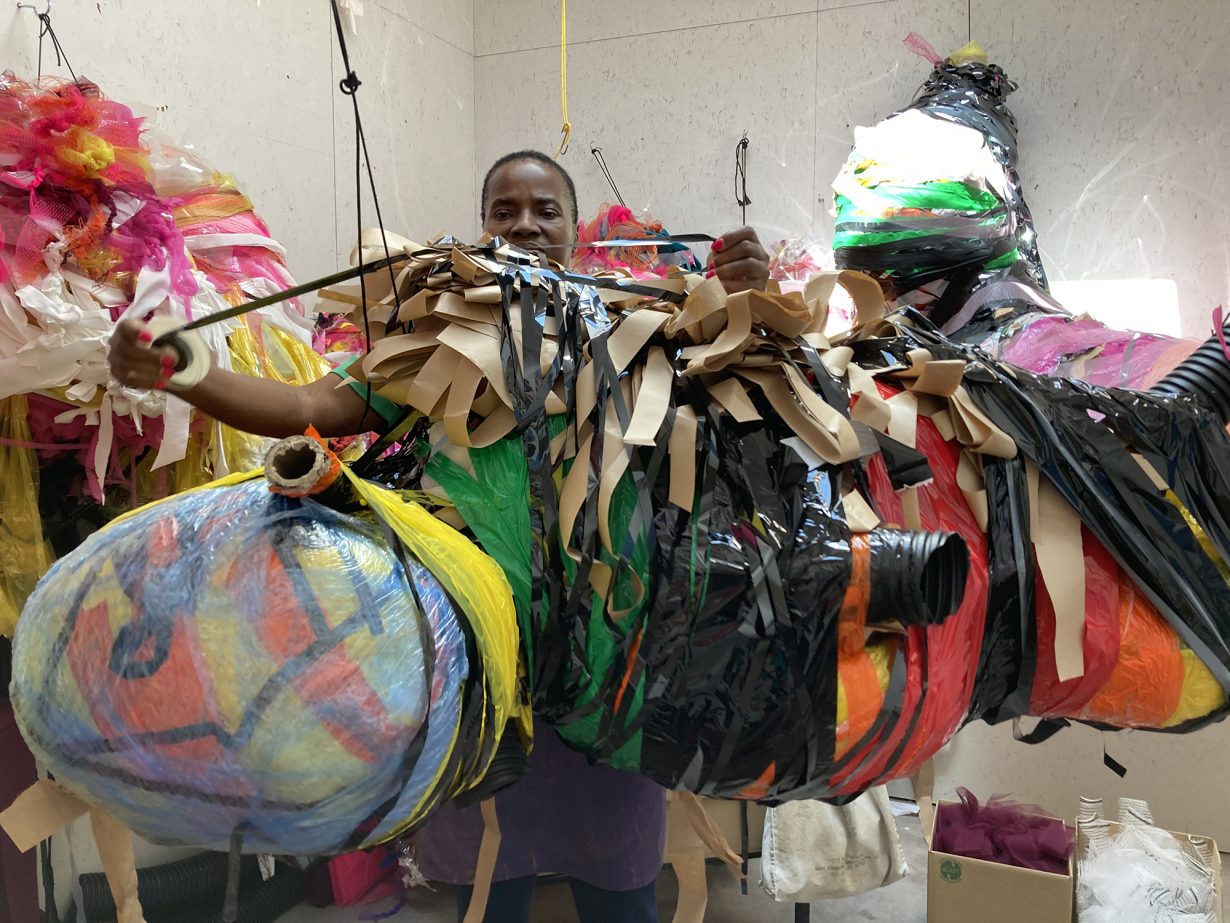 Nnena Kalu, in her studio, working on a colourful, large mixed media hanging sculpture.