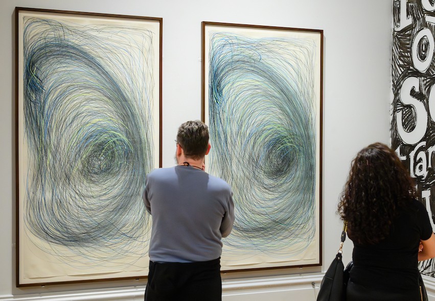 A man looking at Nnena Kalu's artwork in a gallery.