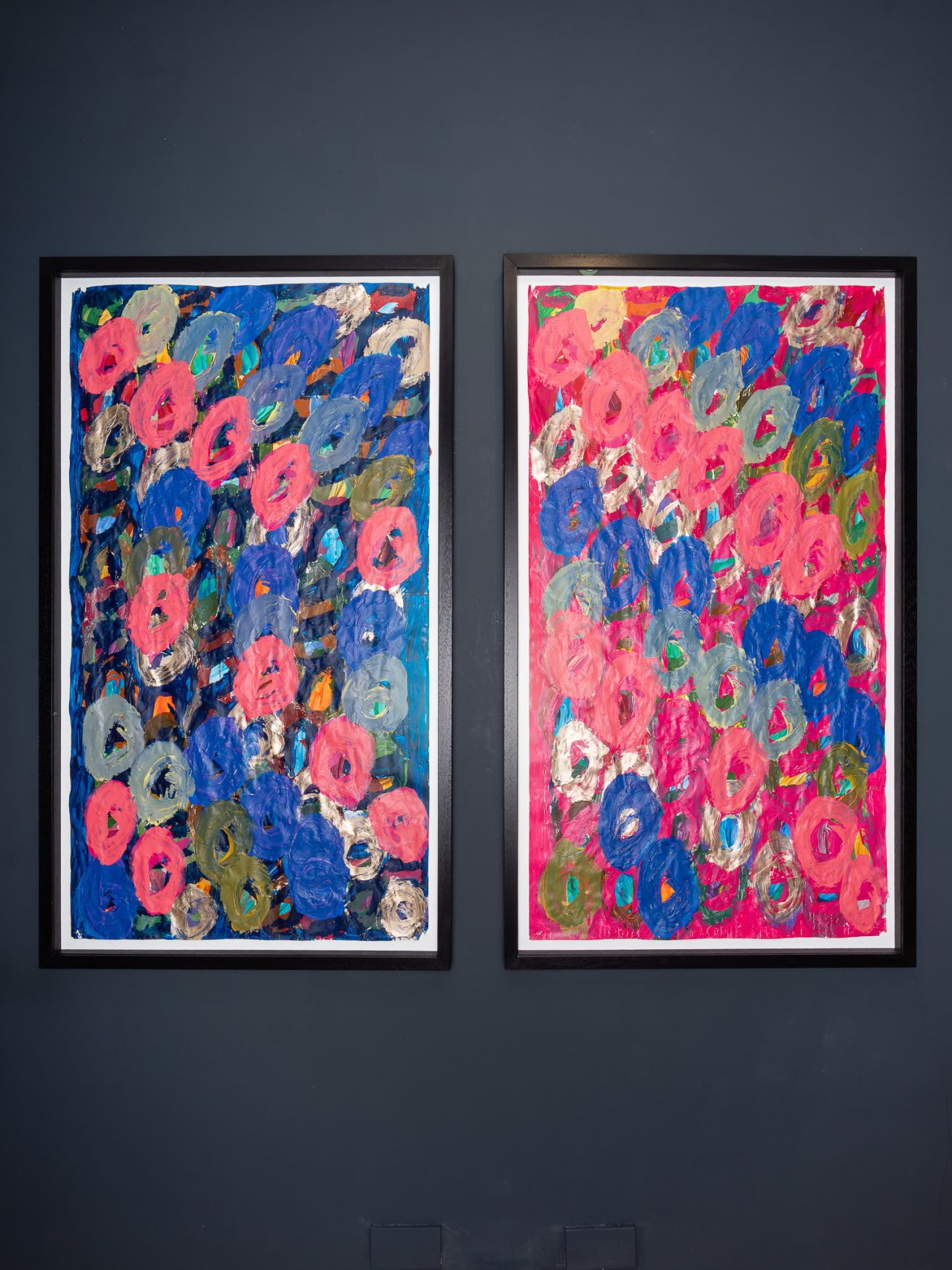 Two abstract paintings by Kwaga Sillingi on a navy gallery wall.