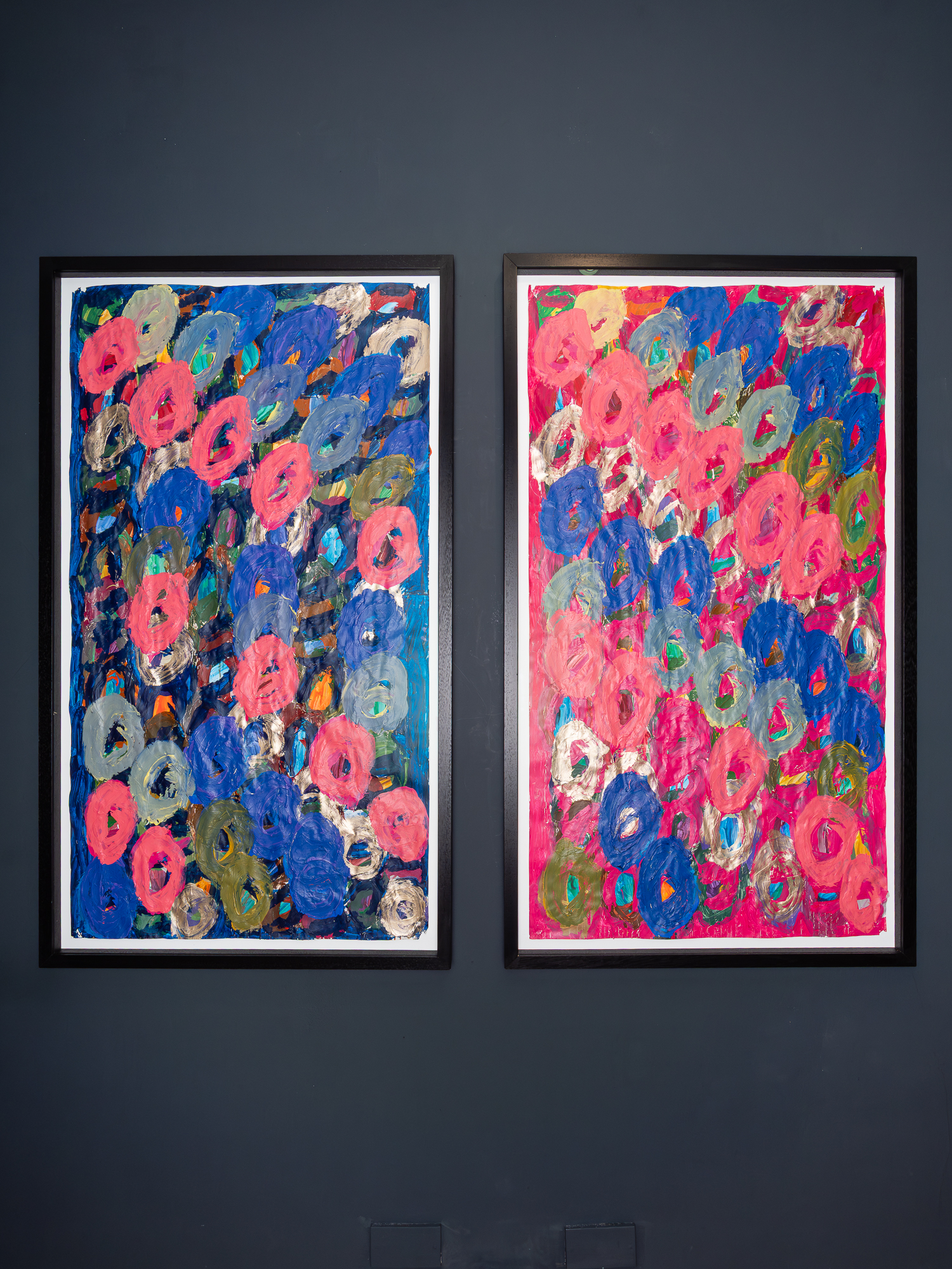 Two abstract paintings by Kwaga Sillingi on a navy gallery wall.