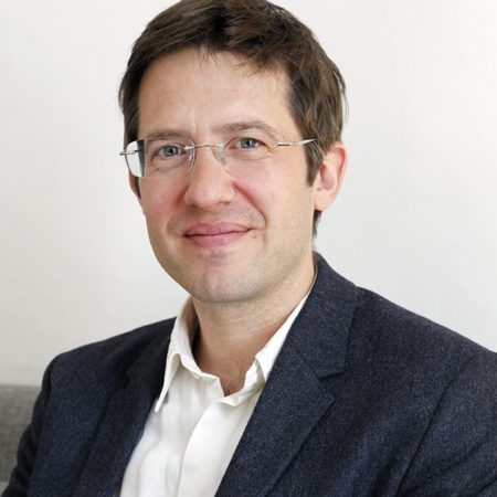 A photo of Anthony Spira. A white man with short brown hair, he is wearing glasses and has a blue suit jacket and a white shirt.