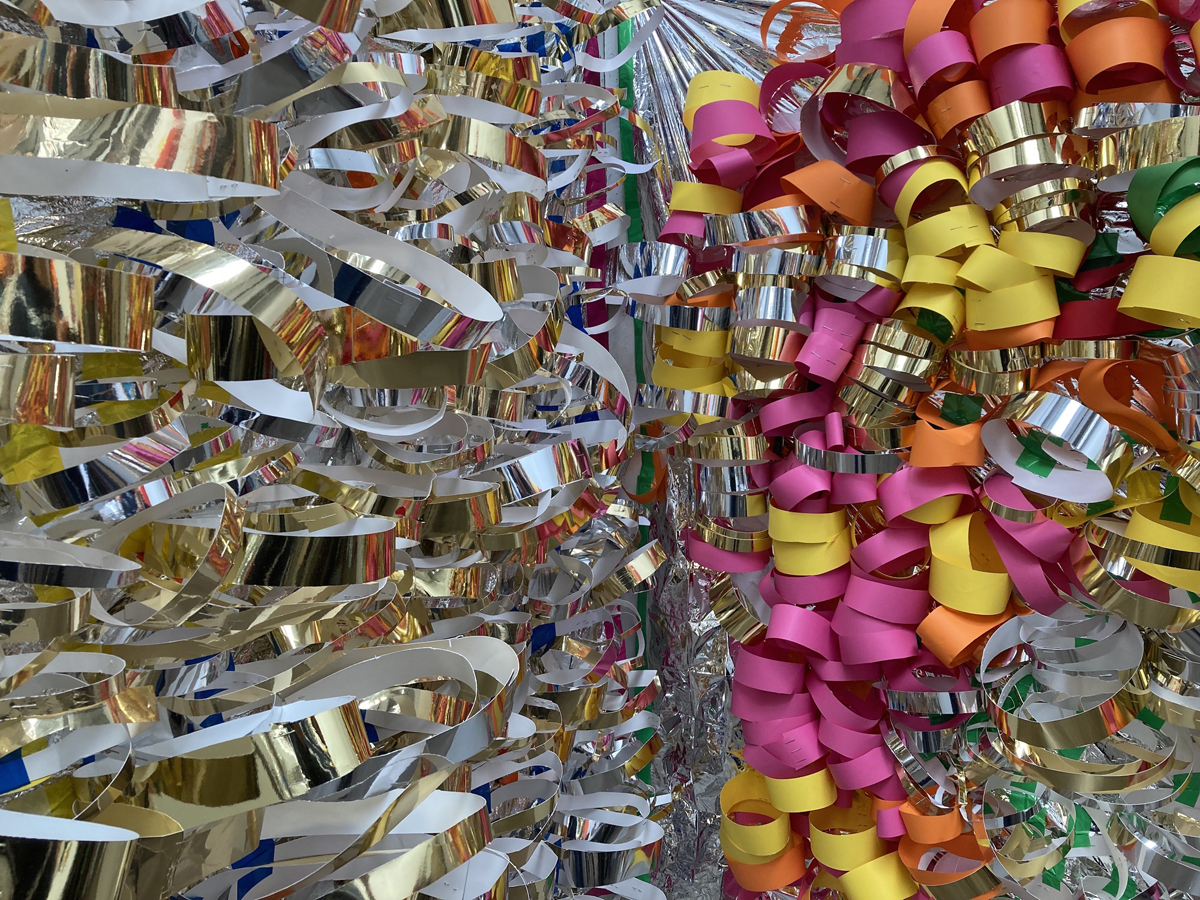 A detail of an artwork. On the left is a silver foil sheet covered in silver and gold loops of card. On the right is the same but the paper loops are pink, yellow, orange and silver.