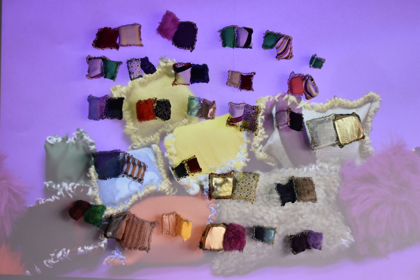 Small textile cushions installed on a wall with a projected image over them.
