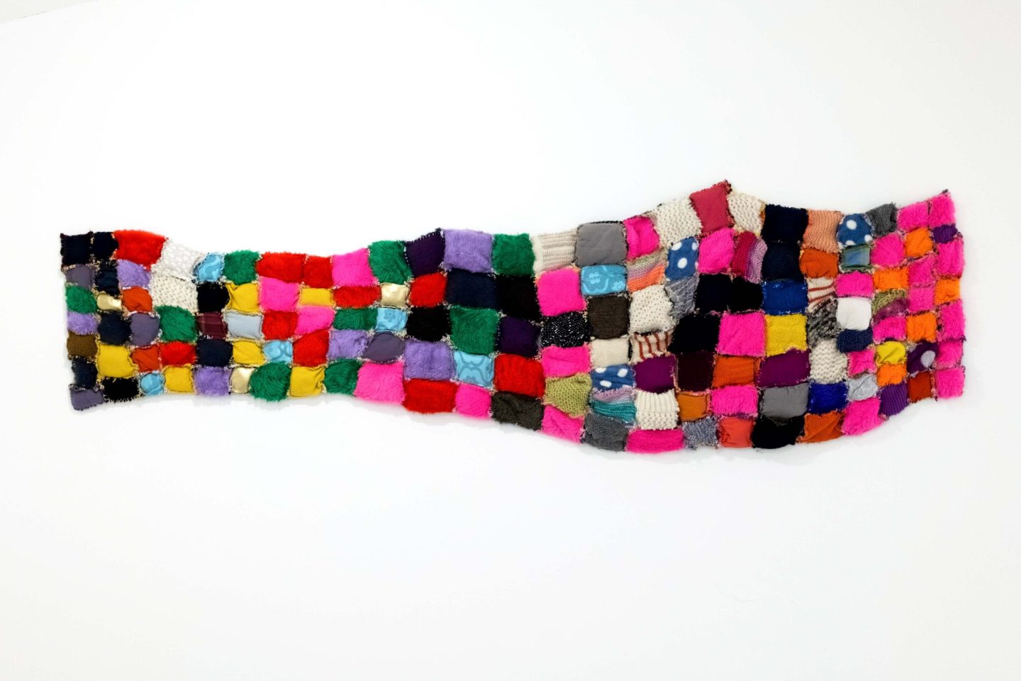 A multicoloured textile quilt made out of patchwork sections.