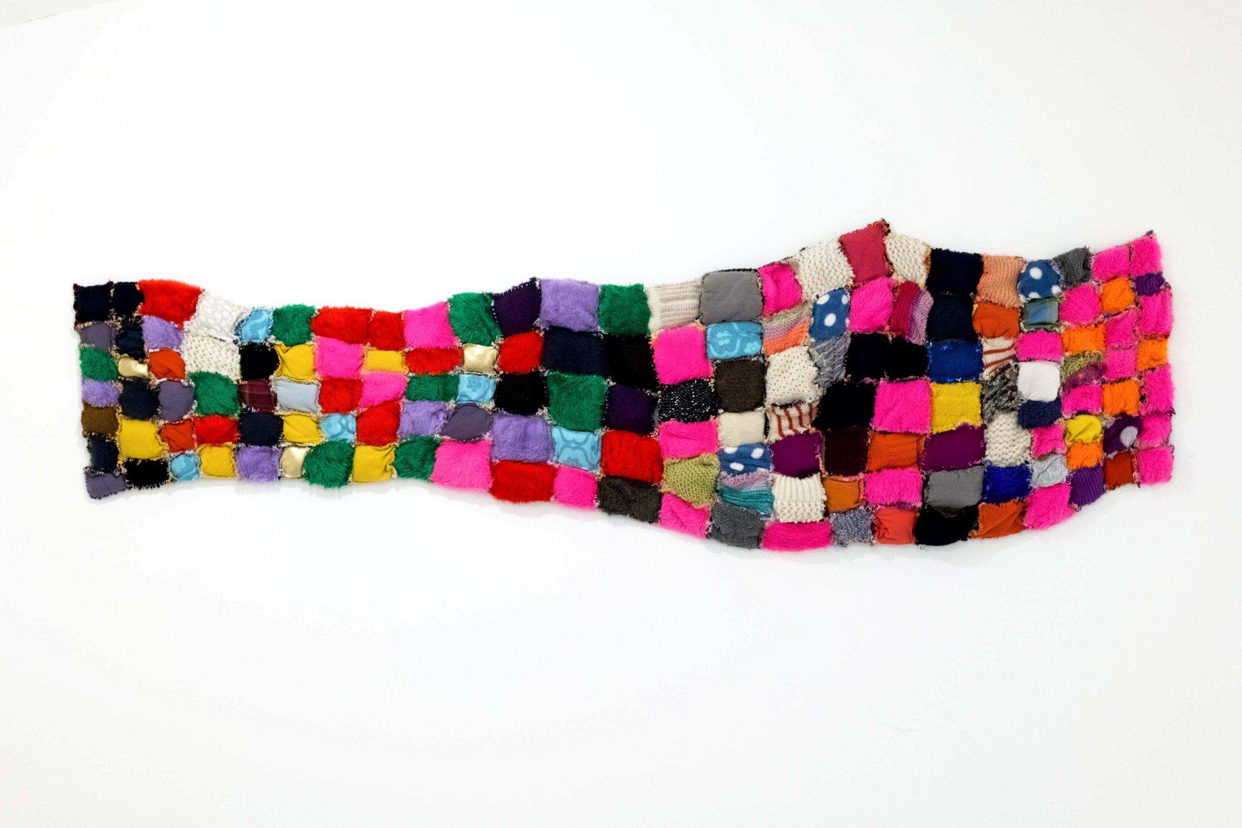 A multicoloured textile quilt made out of patchwork sections.