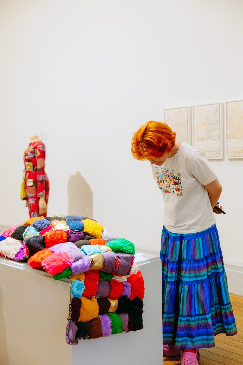 A person looking down at a quilt made by Lasmin Salmon in a gallery.