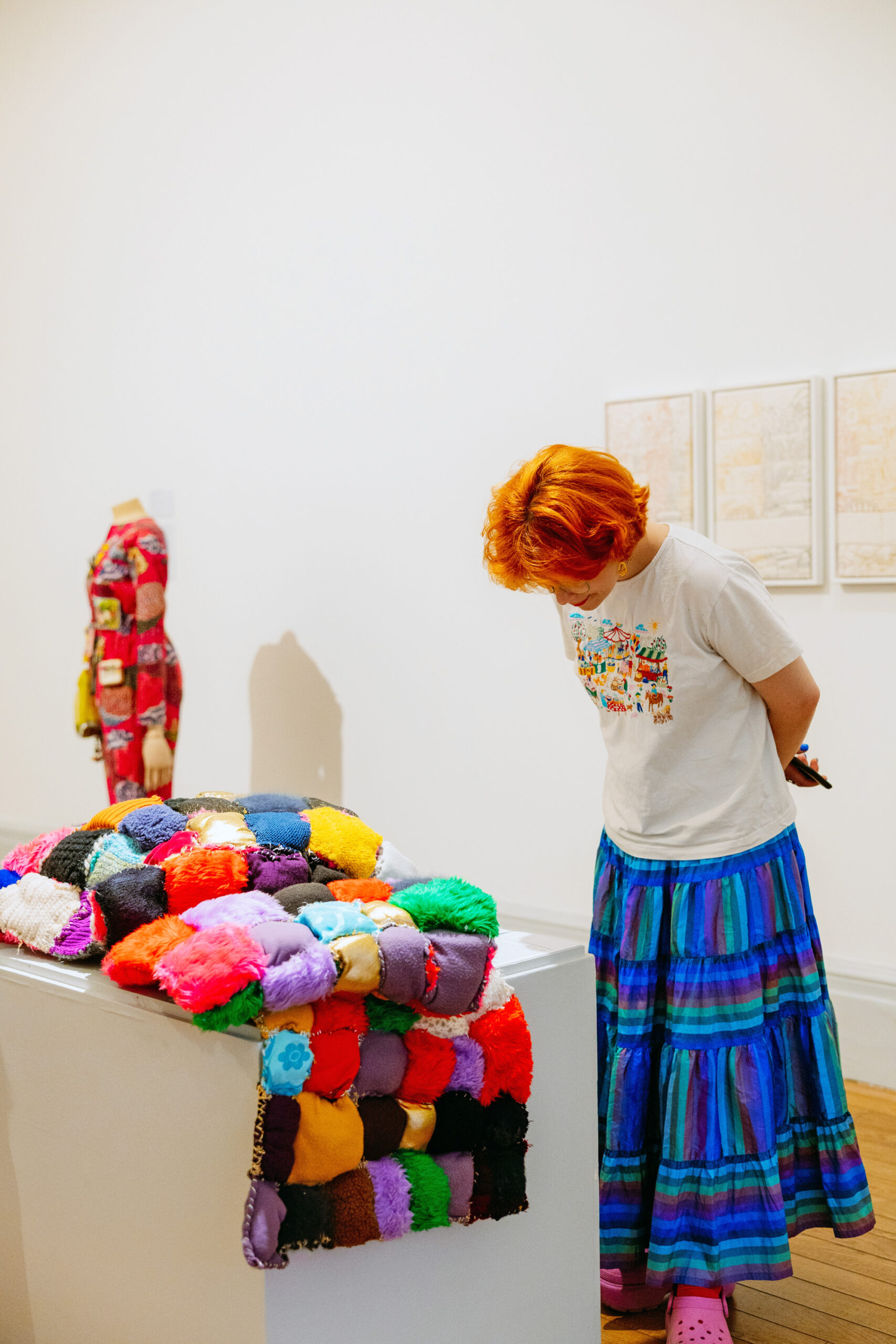 A person looking down at a quilt made by Lasmin Salmon in a gallery.