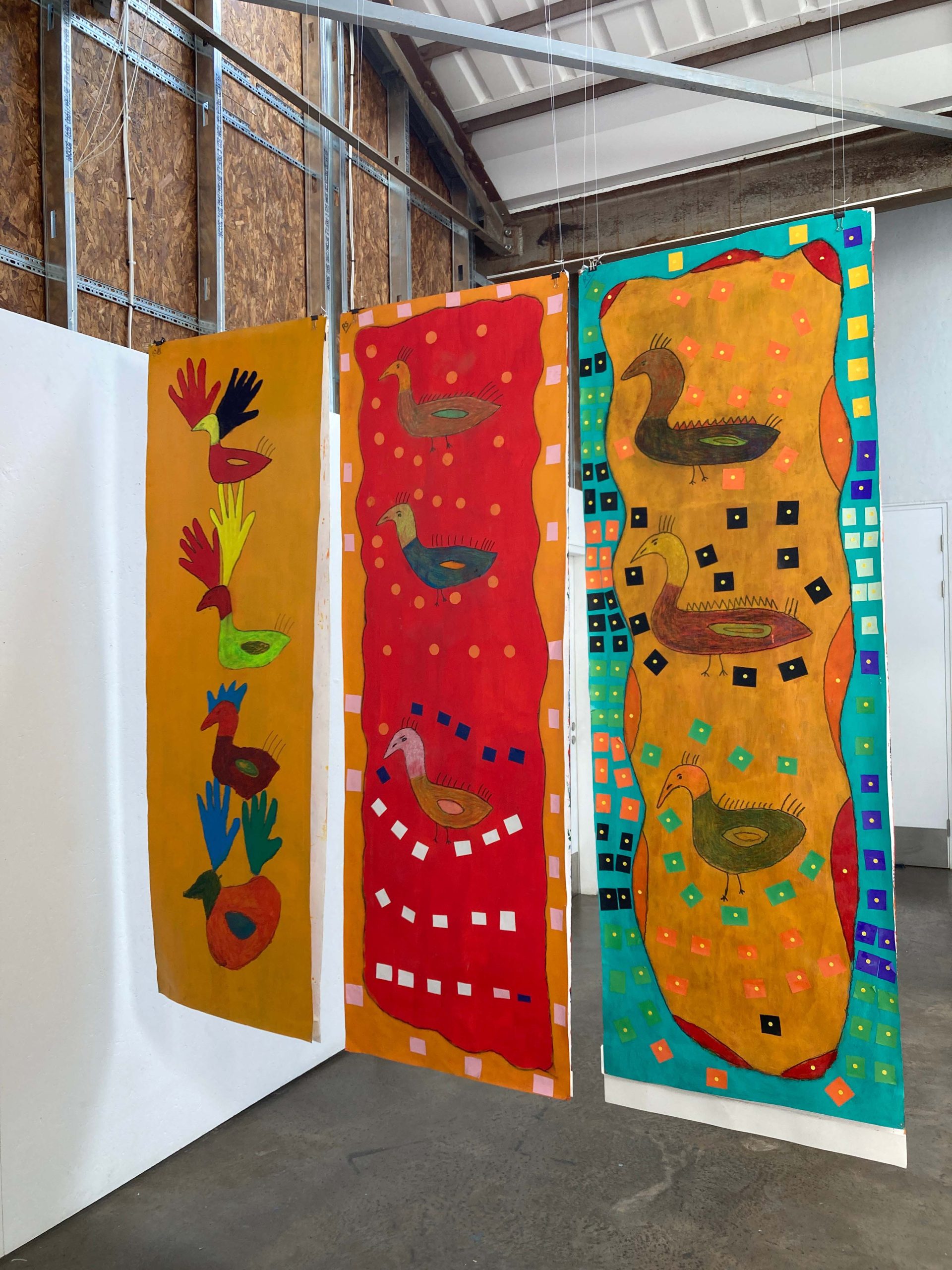Installation view of three long paintings of ducks hanging down from the ceiling.