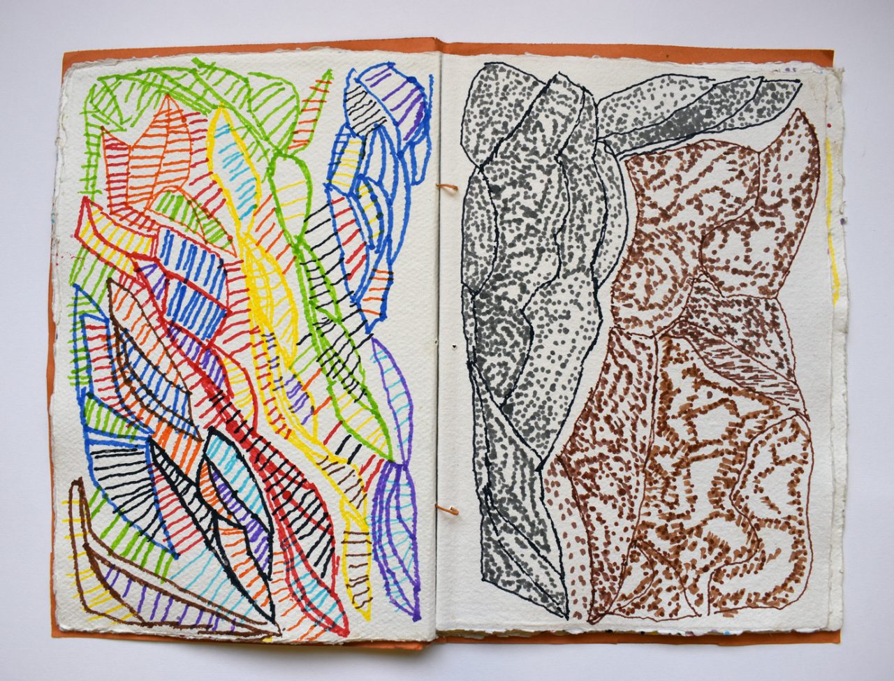 A sketchbook laying open. The pages are filled with colourful drawings in pen.