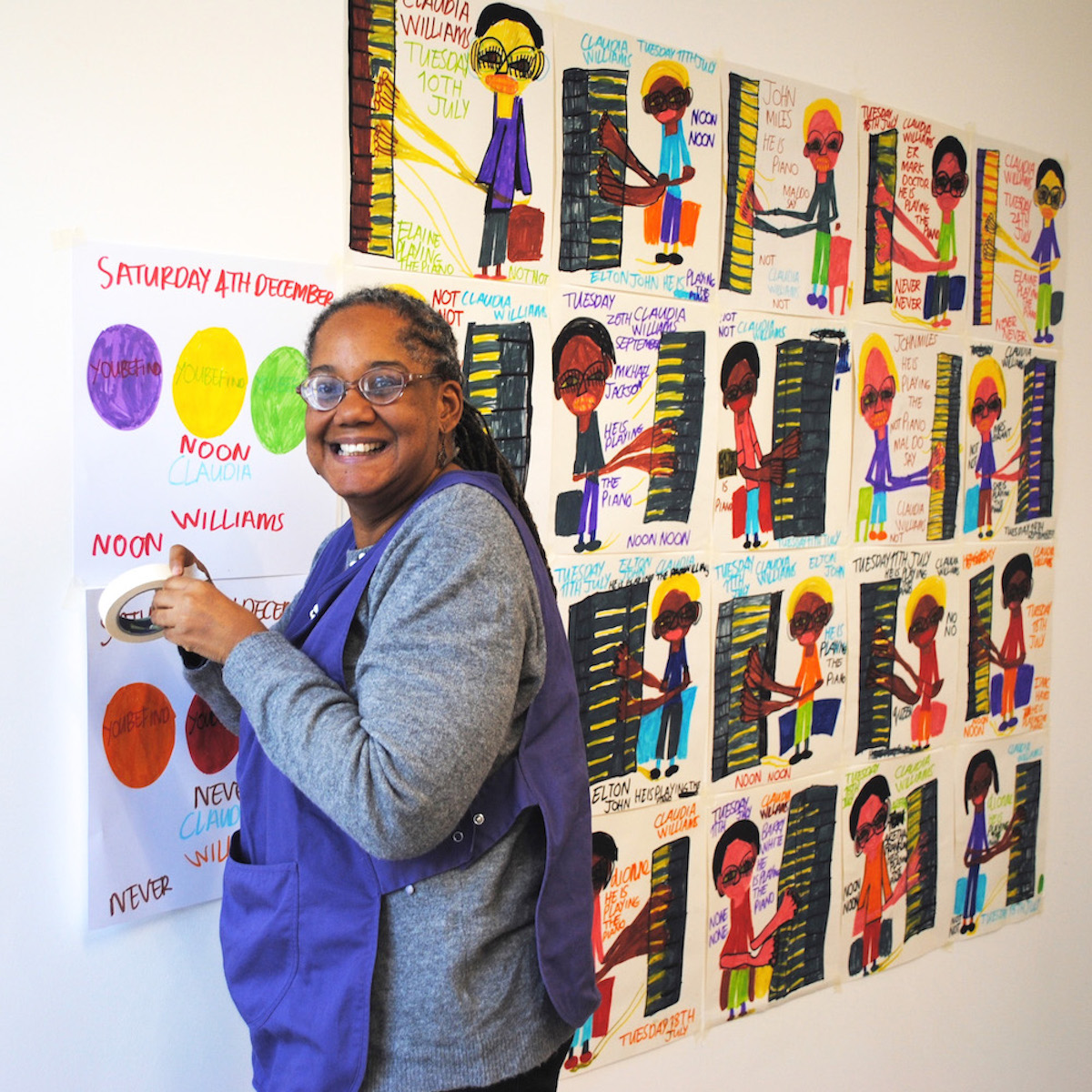 Artist Claudia Williams taping her drawings on the wall.