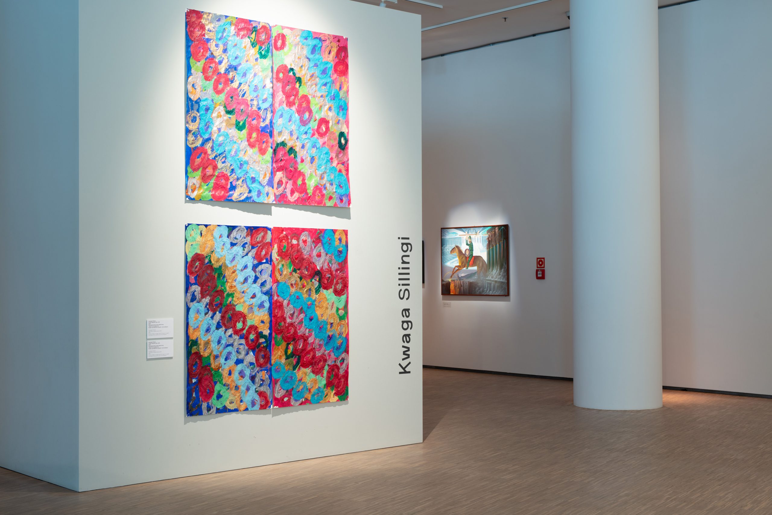Two paintings of layered circles in diagonal coloured stripe formation hangs on display in an exhibition.