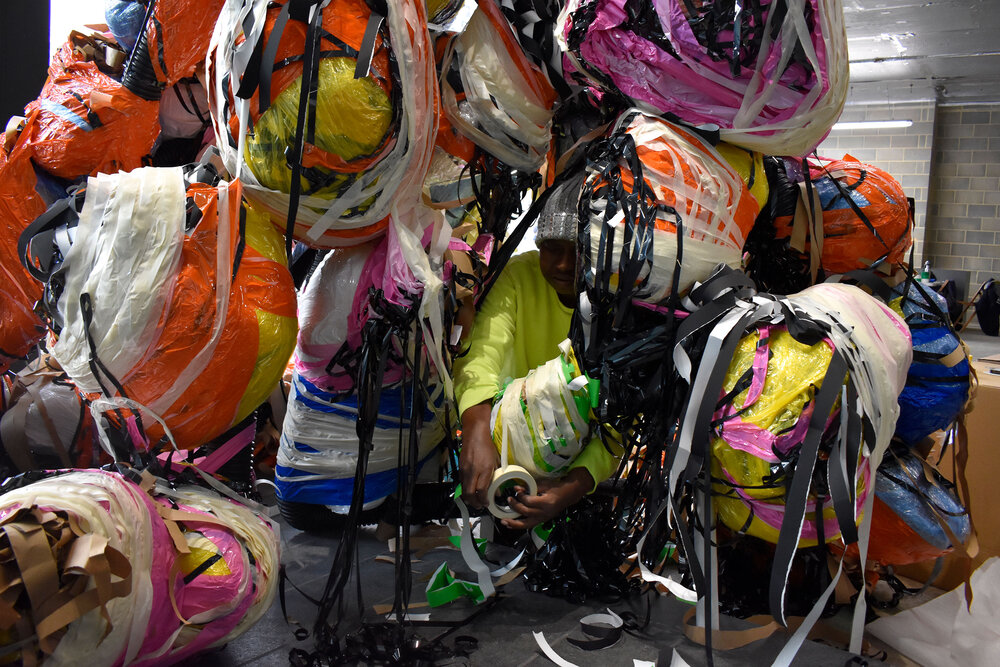 Nnena Kalu, in her studio, working on a colourful, large mixed media hanging sculpture.
