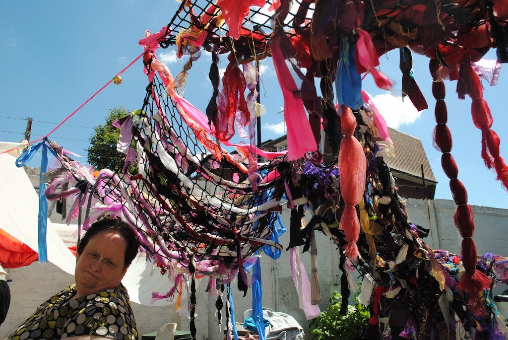 Linda Bell with her work outside on a sunny day. She is smiling at the camera.