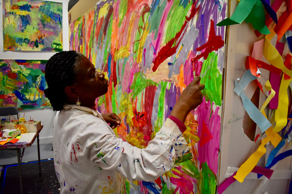 An ActionSpace artist works on her colourful abstract painting.