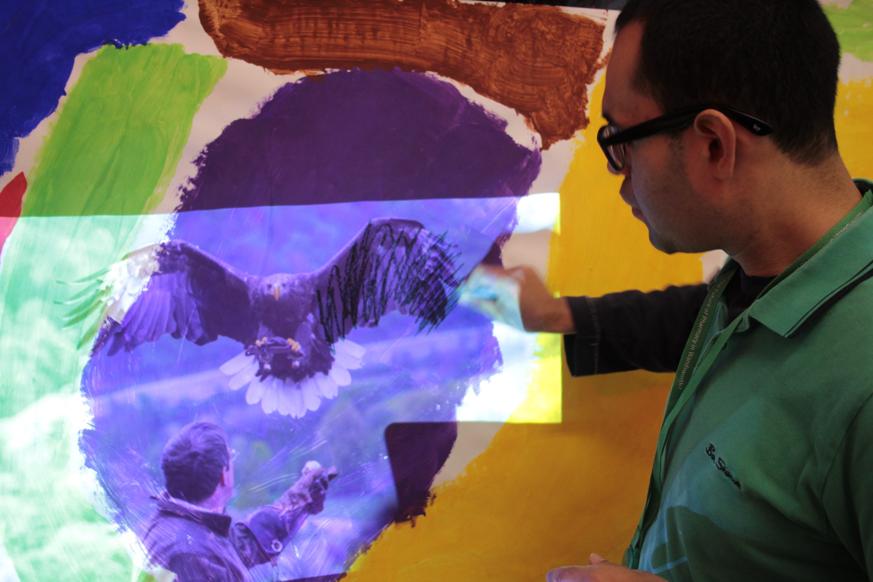 A man draws over a projection of a bird of prey.