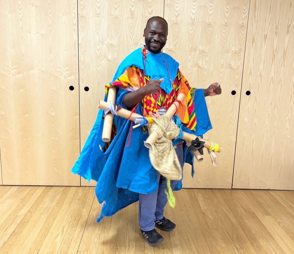 Andrew Omoding stands in a colourful blue outfit.