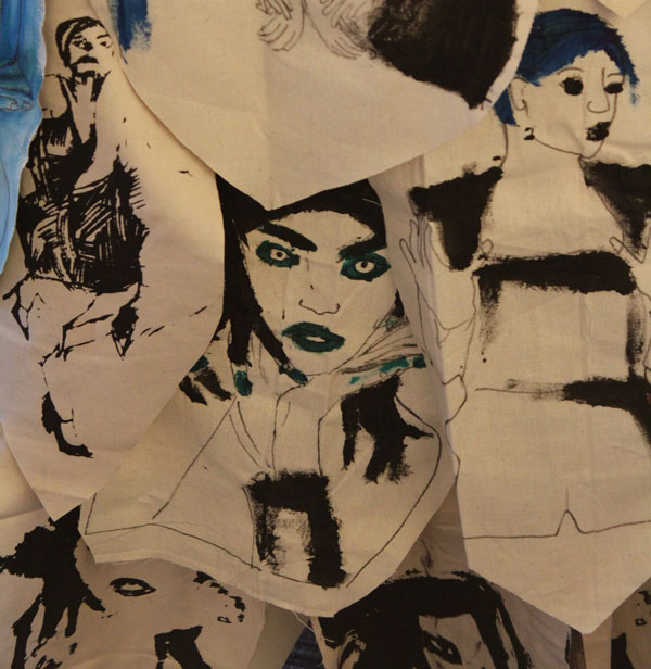 Details of a rag dress made up of layers of painted portraits of women on individual patches of fabric.