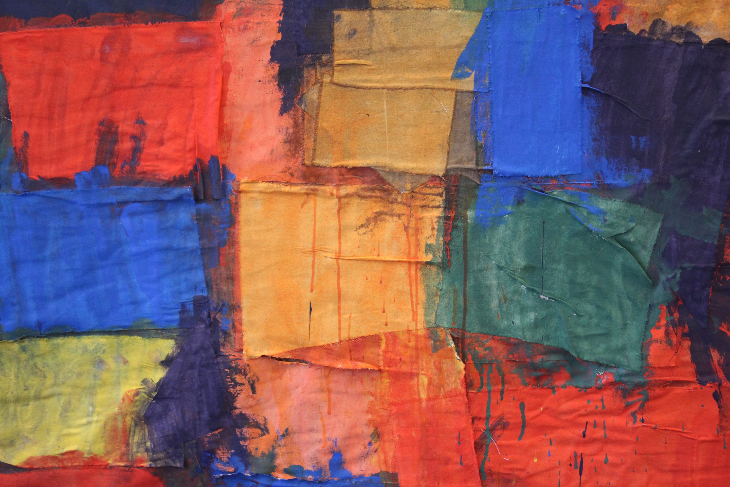 A textile artwork made of layered square patches of fabric painted in different colours.