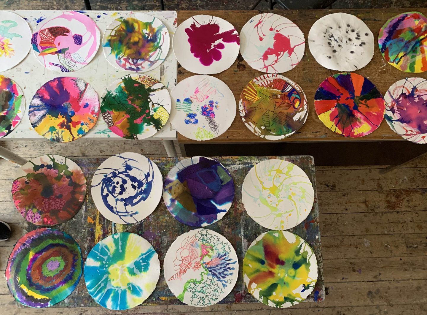 A series of different abstract ink illustrations on circular paper laid out on a table.