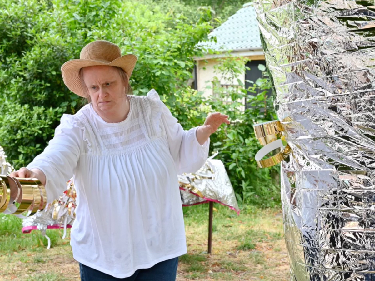 Linda Bell working on a sculpture outside in a green space.