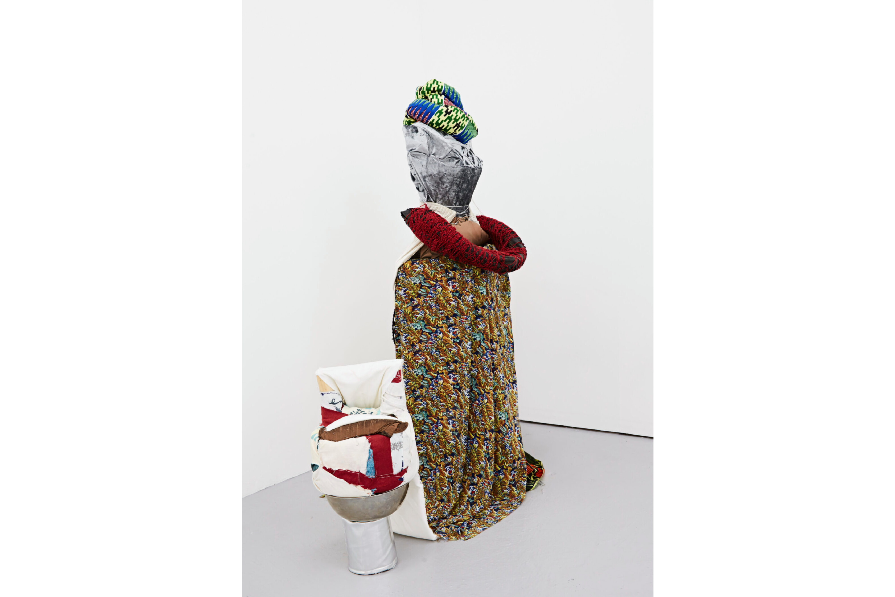 A multimedia textile soft sculpture in the form of a person draped in a cloak.
