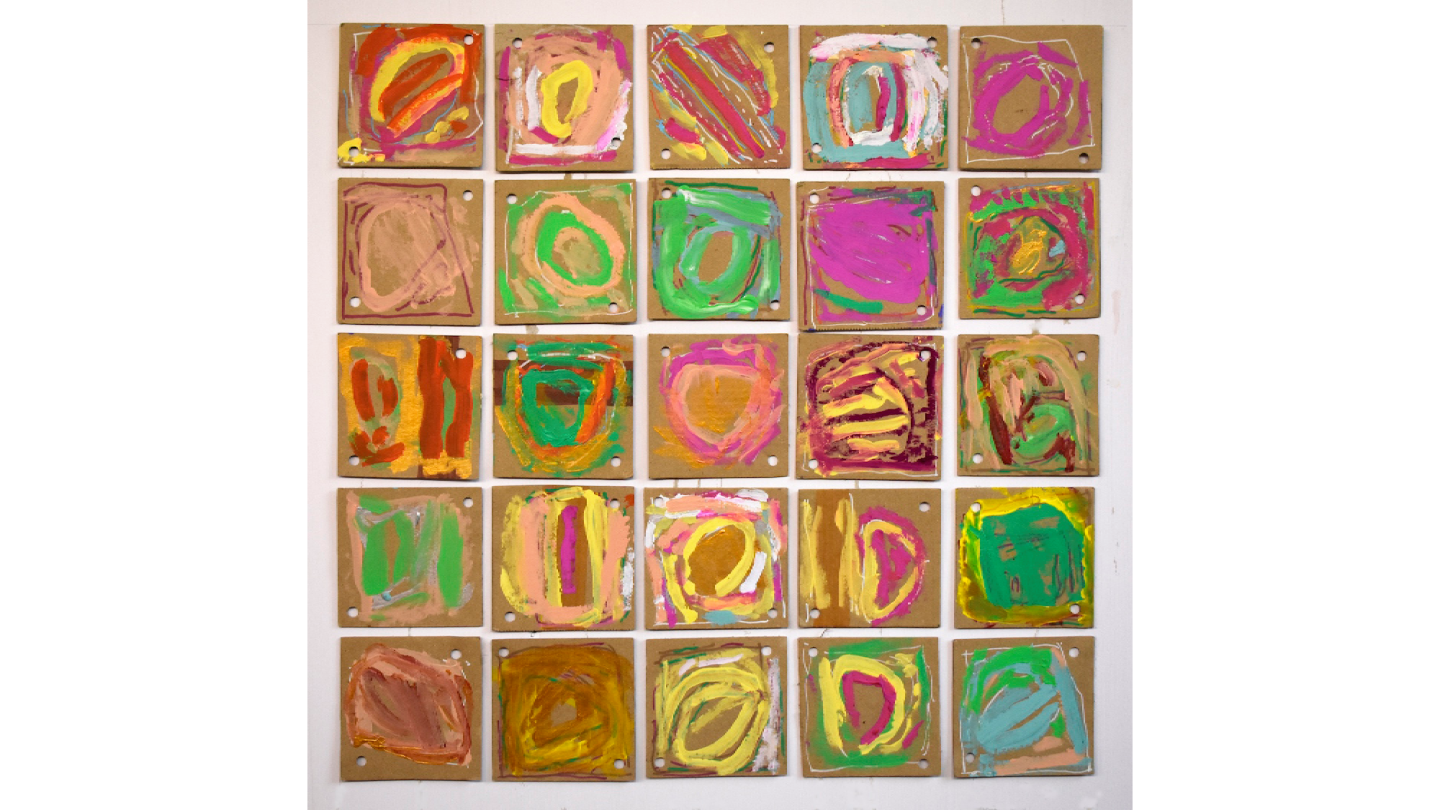 An artwork made on square cardboard tiles with antipodal holes in two corners, that has been laid out in a larger square formation. Bright coloured paint and white pen form gestural and organic cell-like whorl forms.