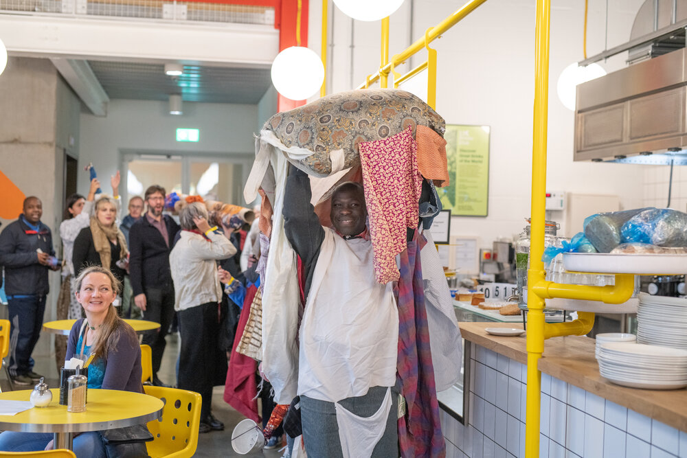 Artist Andrew Omoding holding up a soft sculpture during a performance at Explorers Conference: Art, Rights and Representation.