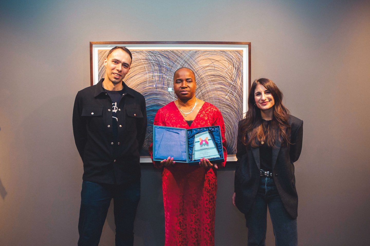 Nnena Kalu with award judges Tim Shaw and Judith Nezri stood in front of one of her hanging artworks.