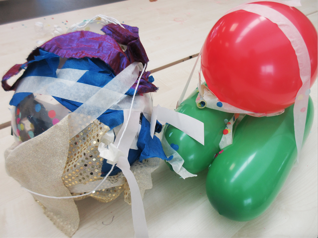 A close-up of balloons on a table with tape and fabric attached to them.