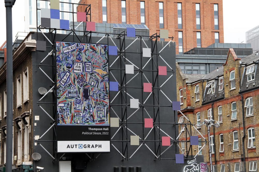 Thompson Hall's work is exhibited on the side of a building. It is a large canvas sheet, with a print of Halls 'political sleaze', 2022 piece on it.