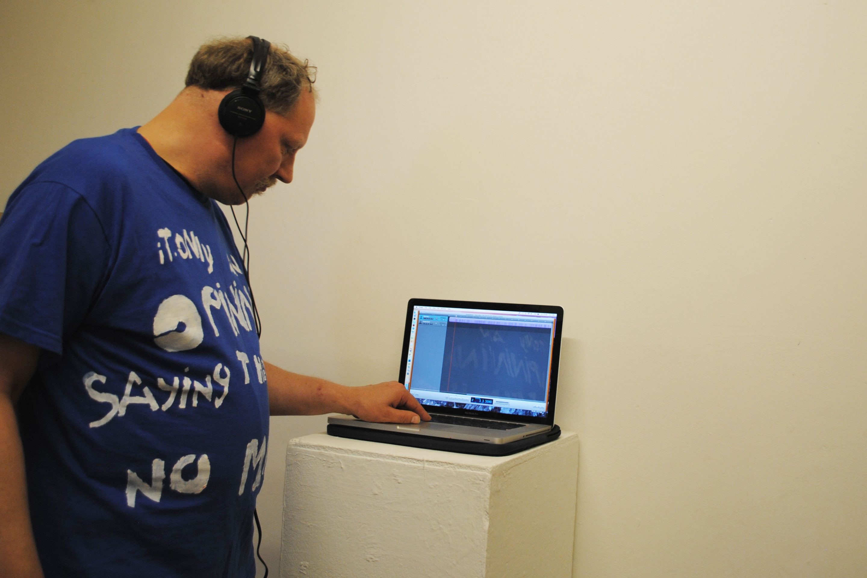 Tony Allen artist portrait. He is looking at a laptop with headphones on.