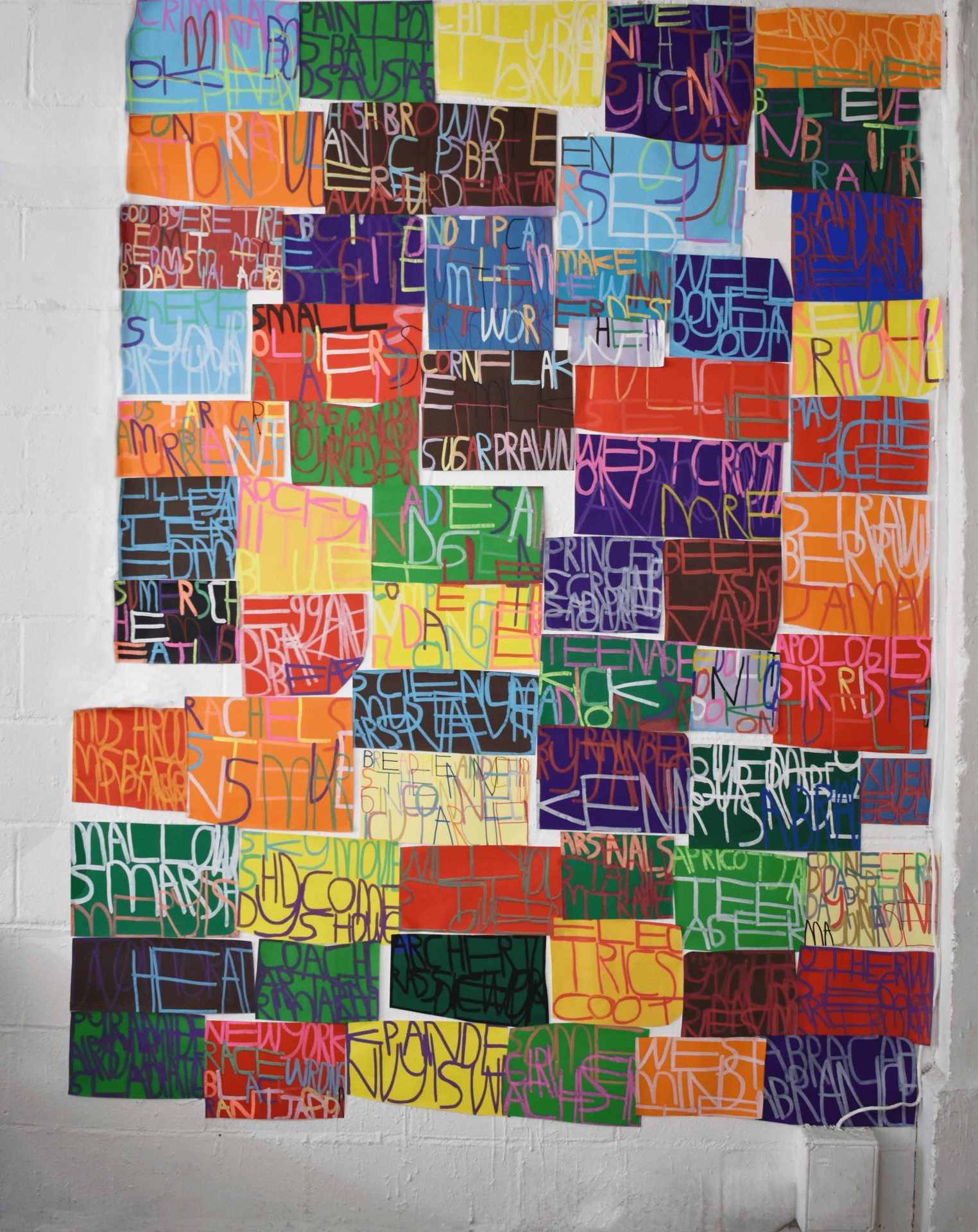 A collage of several dozen artworks by ActionSpace artist Patrick Moses. The works are text based drawings in marker pen on coloured paper.