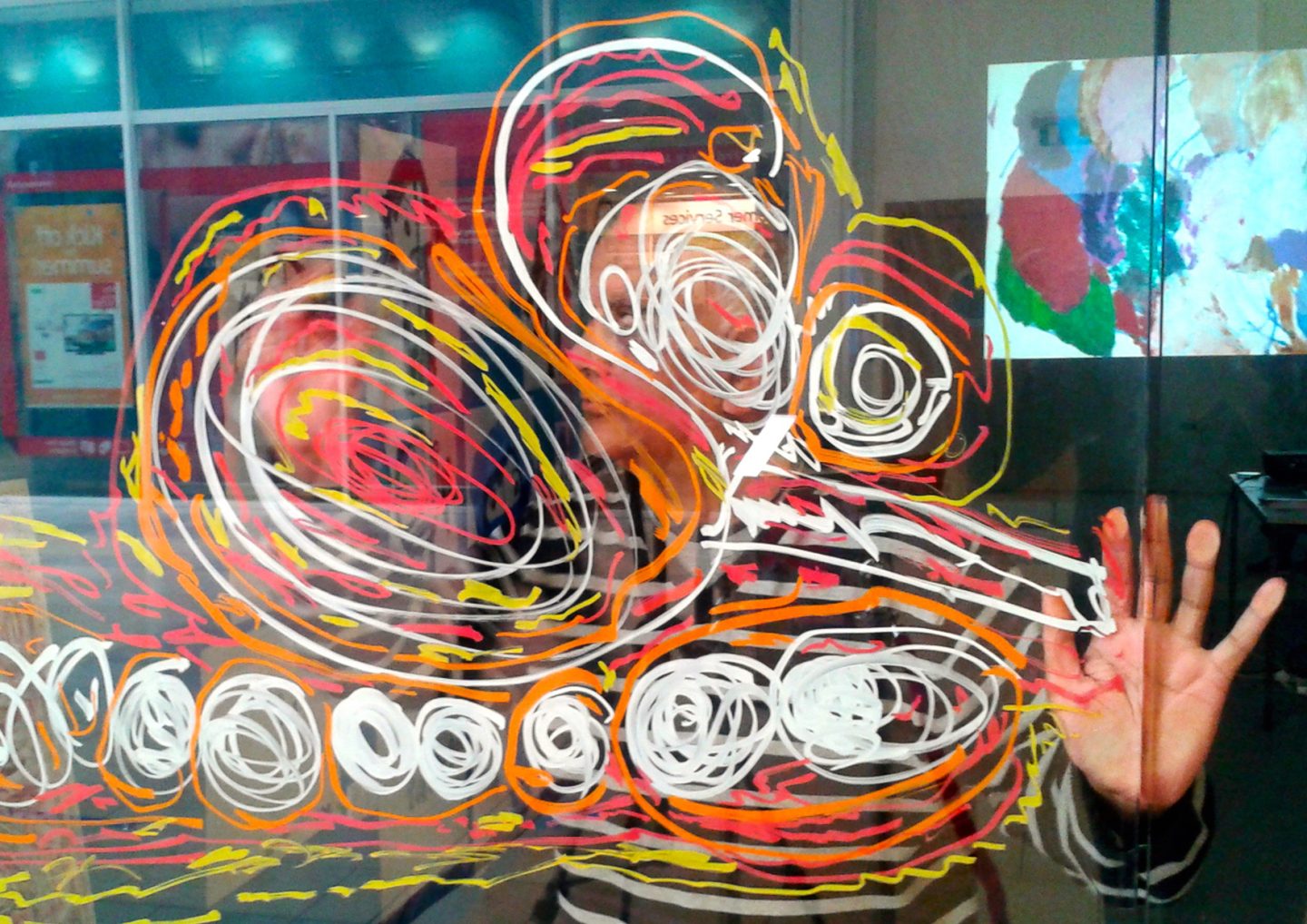 Artist Chandrakant Patel stood on the other side of a window that he has drawn artwork onto.